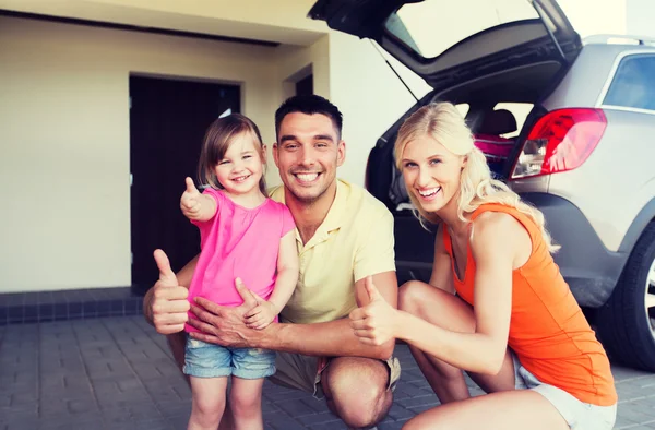 Família feliz com carro mostrando polegares para cima no estacionamento — Fotografia de Stock