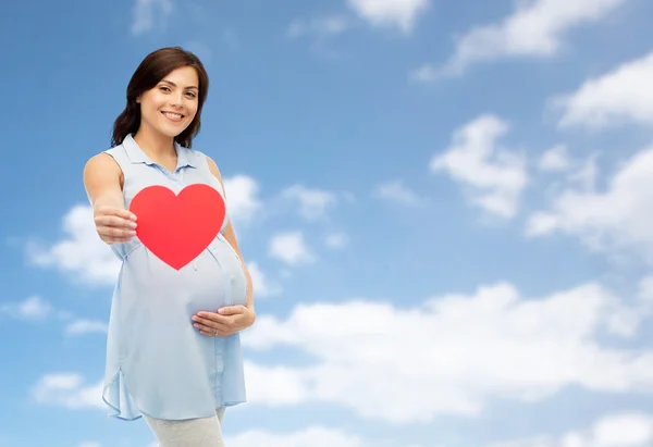 Gelukkig zwangere vrouw met rood hart aanraken van de buik — Stockfoto