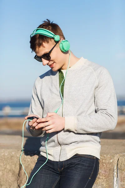 Jovem feliz em fones de ouvido com smartphone — Fotografia de Stock