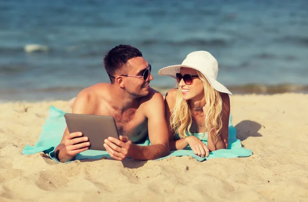 Gelukkige paar met de tablet pc om te zonnebaden op het strand — Stockfoto