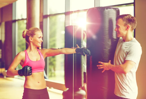 Lächelnde Frau mit Personal Trainer beim Boxen im Fitnessstudio — Stockfoto