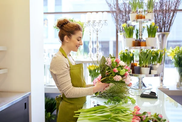 Улыбающаяся цветочница делает букет в цветочном магазине — стоковое фото