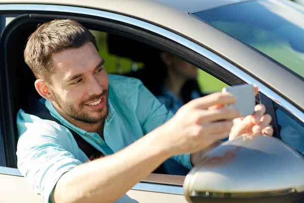 Happy smiling man with smartphone driving in car — Stock Photo, Image