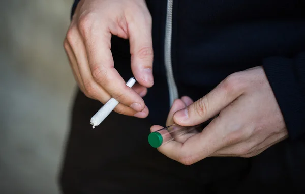 Close-up de mãos viciadas com tubo comum de maconha — Fotografia de Stock