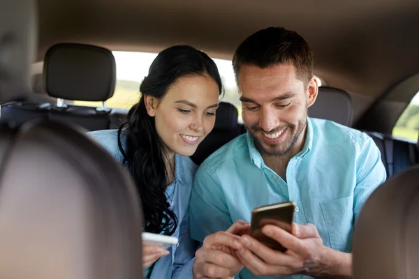 Hombre y mujer con teléfonos inteligentes que conducen en coche —  Fotos de Stock