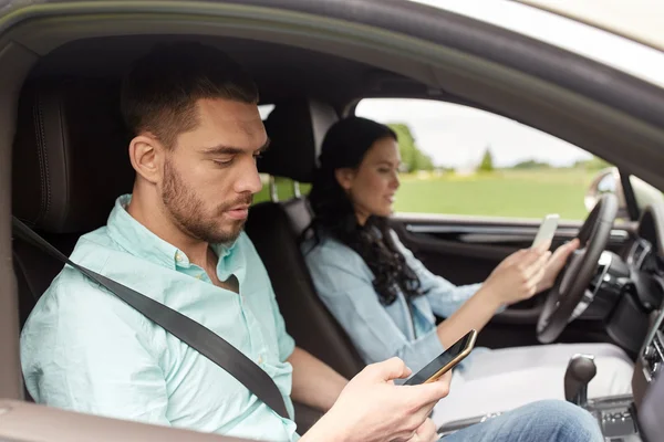 Homem e mulher com smartphones dirigindo no carro — Fotografia de Stock