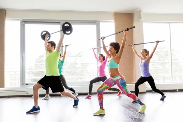 Glückliche Menschen beim Training mit Langhantelstangen im Fitnessstudio — Stockfoto