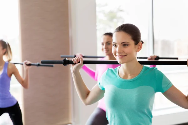 Gruppe glücklicher Frauen mit Balken, die im Fitnessstudio trainieren — Stockfoto
