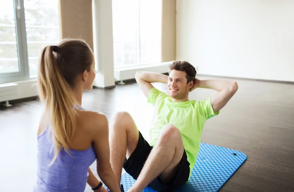 Kvinna med personlig tränare gör sit ups i gym — Stockfoto