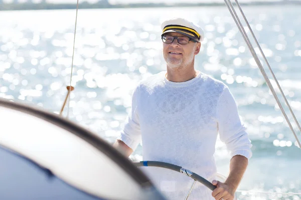 Homem sênior no leme em barco ou iate navegando no mar — Fotografia de Stock