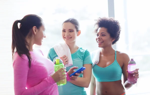 Happy women with bottles of water in gym — Stock Photo, Image