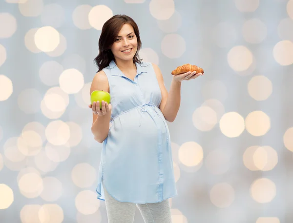 Glückliche Schwangere mit Apfel und Croissant — Stockfoto