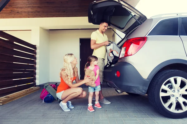 Lycklig familj packar saker till bilen hemma parkering — Stockfoto