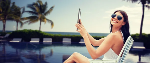 Mulher sorridente com tablet pc banhos de sol na praia — Fotografia de Stock