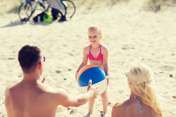 Familia feliz jugando con la bola inflable en la playa —  Fotos de Stock