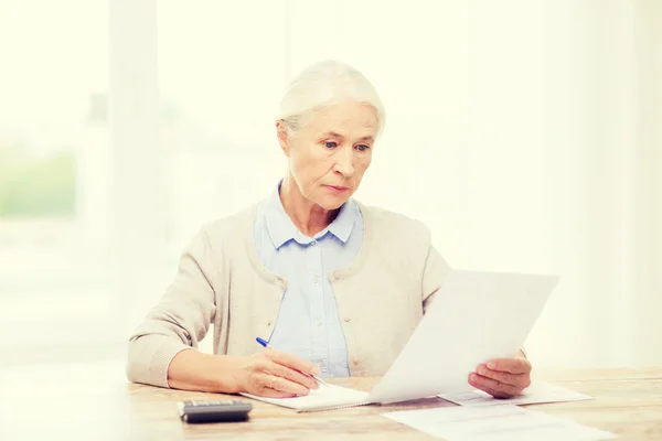 Senior woman with papers and calculator at home — Stock Photo, Image