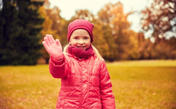 Feliz niña saludando de la mano en el parque de otoño — Foto de Stock