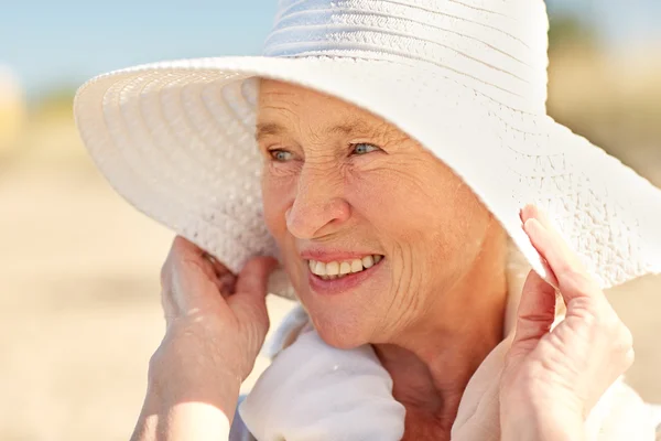 Mulher sênior feliz em chapéu de sol na praia de verão — Fotografia de Stock