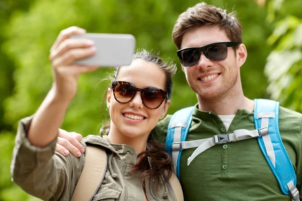 Couple with backpacks taking selfie by smartphone — Stock Photo, Image