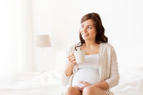 Gelukkig zwangere vrouw met kop thee drinken thuis — Stockfoto