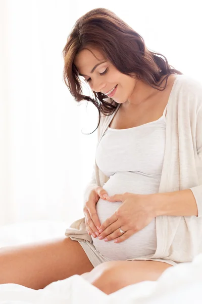 Gelukkig zwangere vrouw hart gebaar thuis — Stockfoto