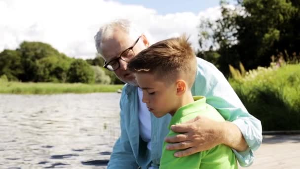 Avô e neto sentados no cais do rio 25 — Vídeo de Stock