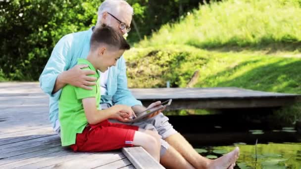 Avô e menino com tablet pc no cais do rio 33 — Vídeo de Stock