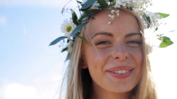 Jonge vrouw in een krans van bloemen buiten glimlachen — Stockvideo