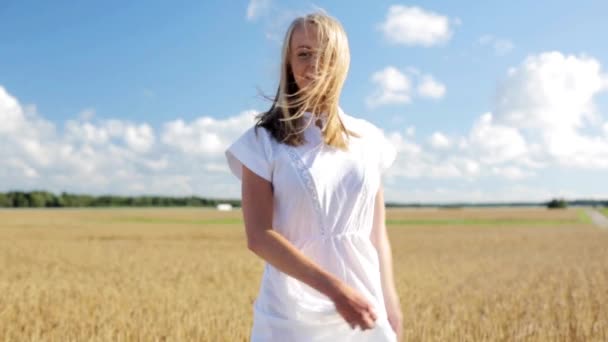 Glimlachende jonge vrouw in witte jurk op graanveld — Stockvideo