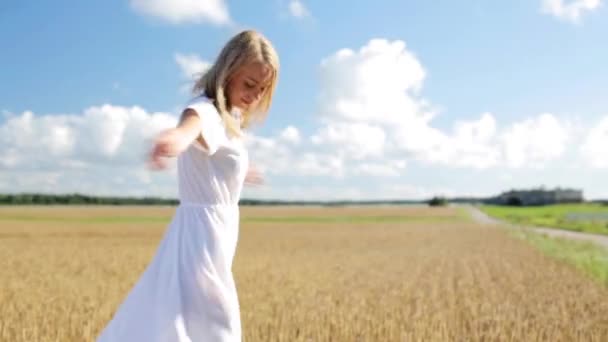 Glimlachende jonge vrouw in witte jurk op graanveld — Stockvideo