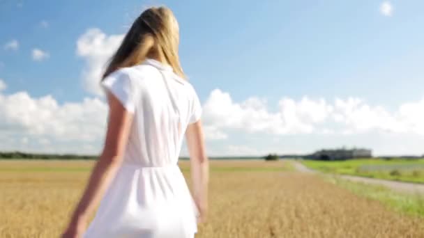 Улыбающаяся молодая женщина в белом платье на зерновом поле — стоковое видео