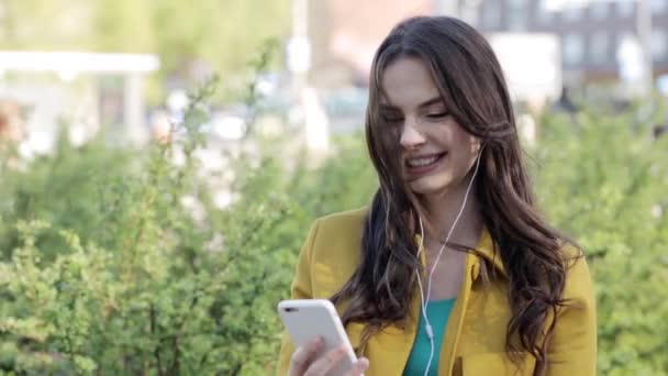 Счастливая молодая женщина со смартфоном и наушниками — стоковое видео