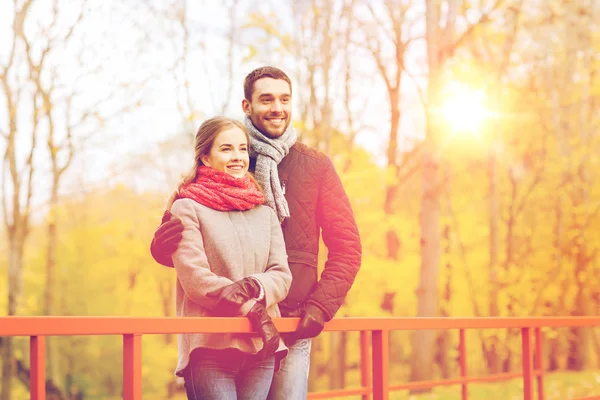 Smiling couple hugging on bridge in autumn park — Stock Photo, Image