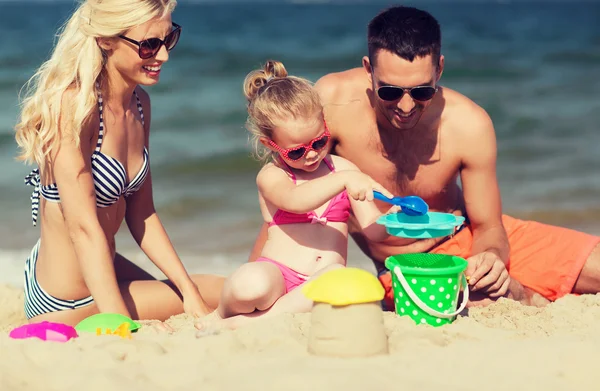 Lyckliga familjen leker med sand leksaker på stranden — Stockfoto