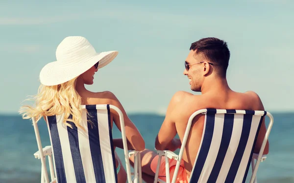 Feliz pareja tomando el sol en sillas en la playa de verano —  Fotos de Stock