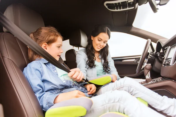 Feliz mujer sujeción niño con cinturón de seguridad en el coche — Foto de Stock