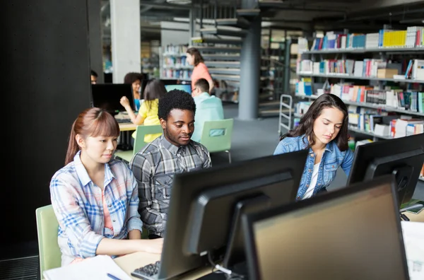 Estudantes internacionais com computadores na biblioteca — Fotografia de Stock