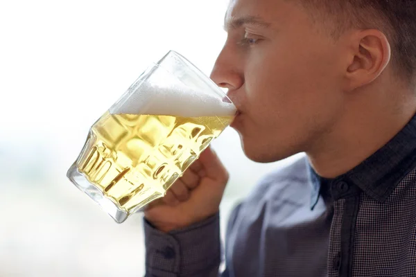 Close up of young man drinking beer from glass mug — Stock Photo, Image