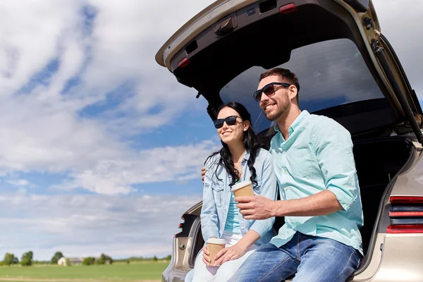 Casal feliz com café no porta-malas do carro hatchback — Fotografia de Stock