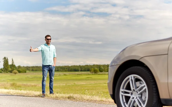 Man hitchhiking and stopping car at countryside — Stock Photo, Image