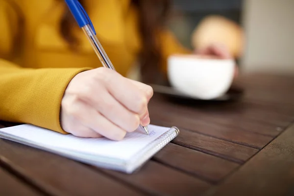 Close up of hand writing to notebook at cafe Stock Image