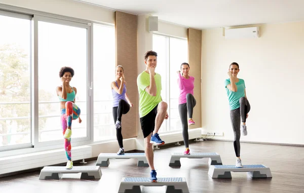 Grupo de personas que hacen ejercicio en los pasos en el gimnasio — Foto de Stock