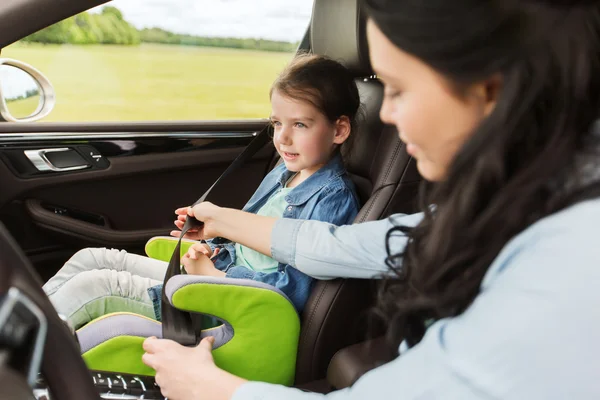 Feliz mujer sujeción niño con cinturón de seguridad en el coche — Foto de Stock