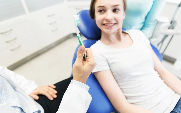 Menutup tangan dokter gigi dengan sikat gigi dan gadis — Stok Foto