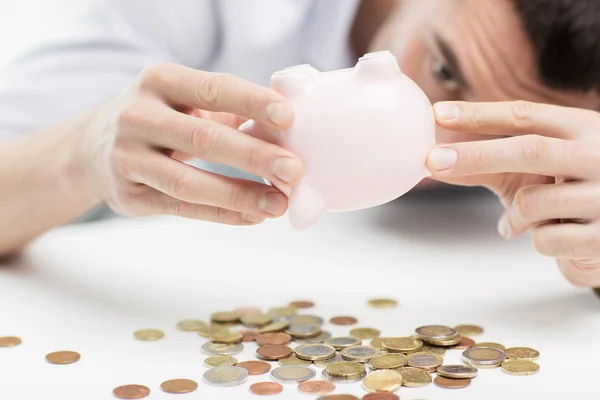 Close up of man pouring coins from piggy bank Stock Photo