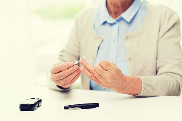 Mulher idosa com glicosímetro a verificar o açúcar no sangue — Fotografia de Stock