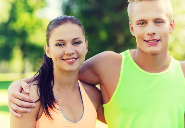 Amigos felices o deportistas pareja abrazándose al aire libre — Foto de Stock