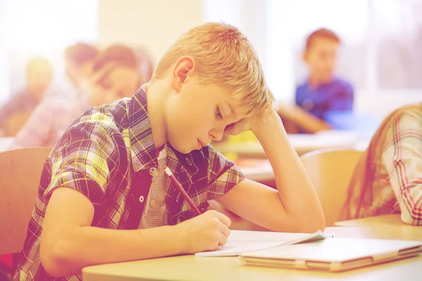 Grupp av skolbarnen skriva prov i klassrummet — Stockfoto