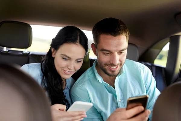 Hombre y mujer con teléfonos inteligentes que conducen en coche —  Fotos de Stock