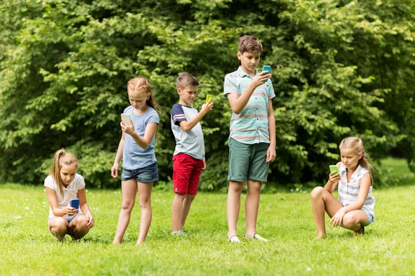 Niños con smartphones jugando en el parque de verano — Foto de Stock
